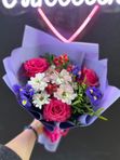 Букет из малиновых роз, синих ирисов и хризантем с добавлением гиперикума   в лавандовом оформлении